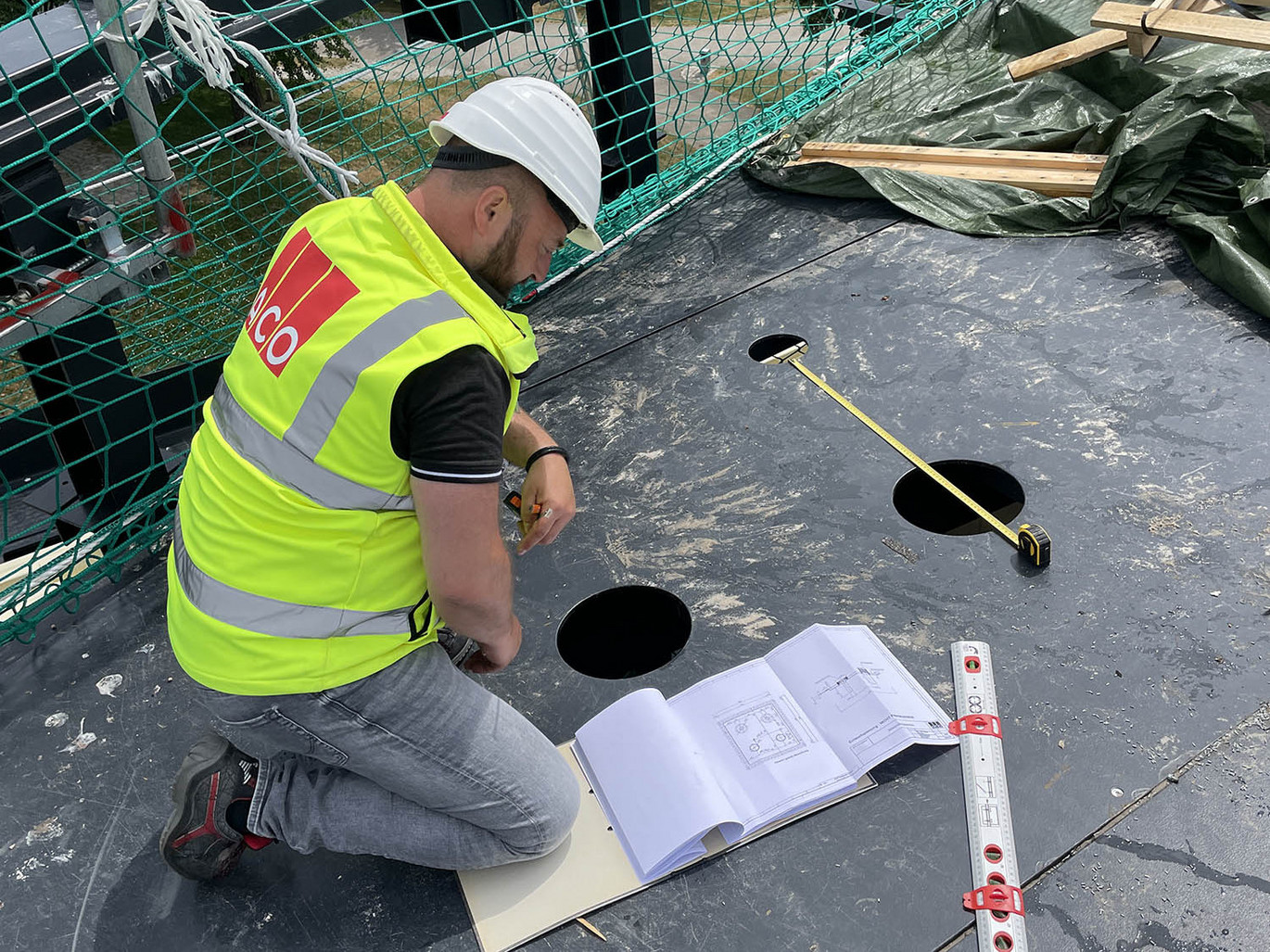 Anwendungstechniker-ACO-Baustelle-Sicherheitsweste-Schutzhelm-Maßband-Bodenbplatte-Baupläne