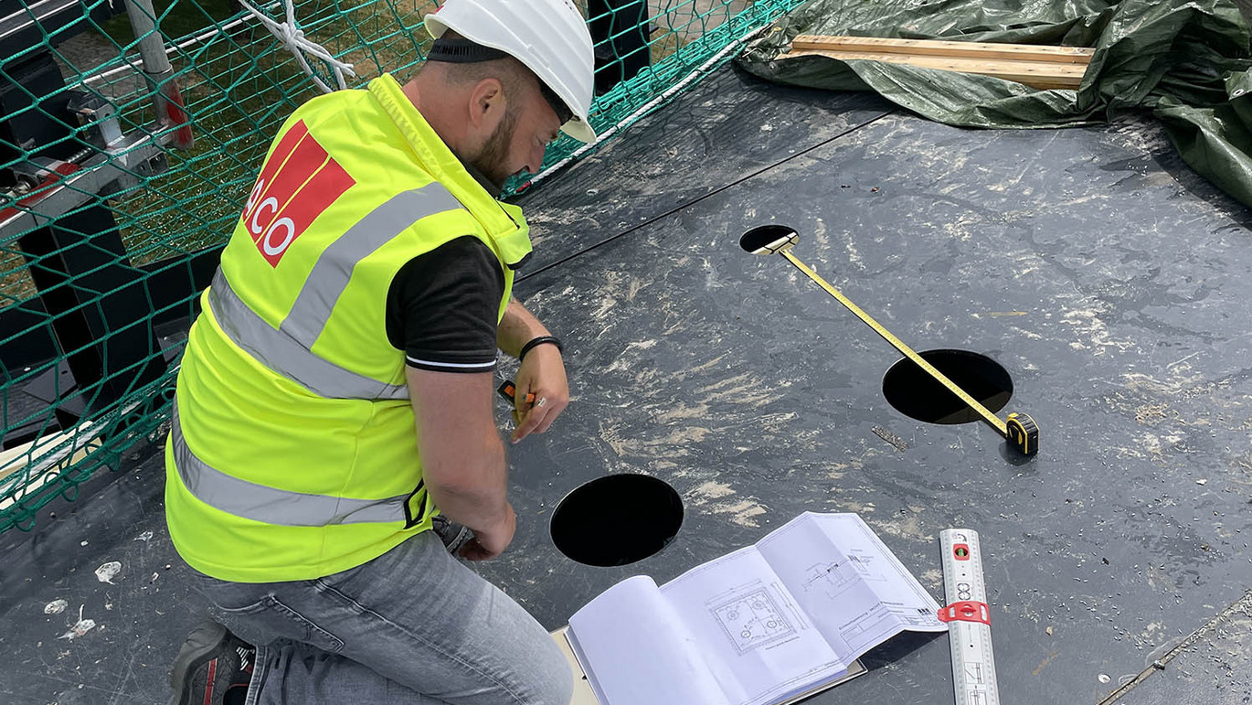 Anwendungstechniker-ACO-Baustelle-Sicherheitsweste-Schutzhelm-Maßband-Bodenbplatte-Baupläne